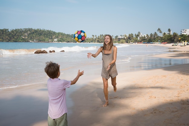 Gelukkig moeder en zoon bal spelen op het strand in zonnige zomerdag