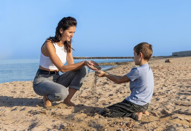 Gelukkig moeder en zoon rennen en spelen op het strand op blote voeten zonnige dag in de buurt van de zee