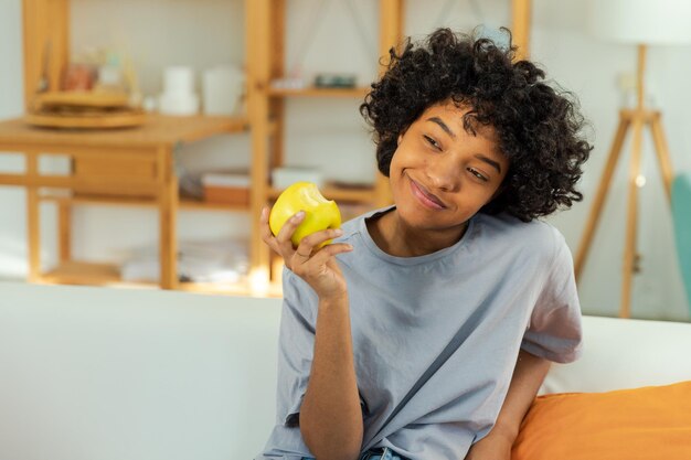 Gelukkig mooi meisje die groene appel thuis bijten mooie Afrikaanse Amerikaanse jonge vrouw die vers fruit eet