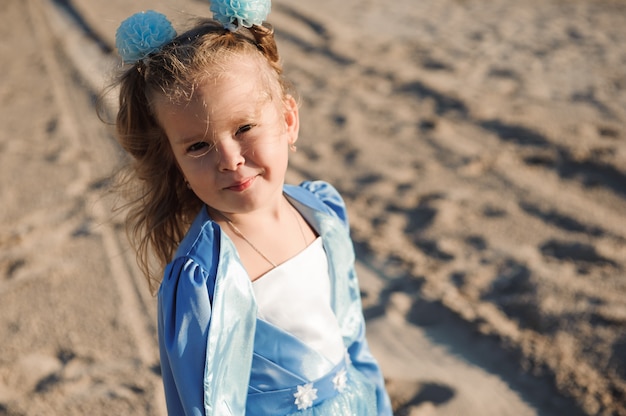 Gelukkig mooi meisje in een blauwe jurk op het strand