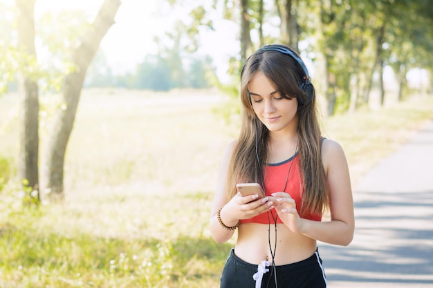 Gelukkig mooi meisje in rode tshirt luisteren naar muziek tijdens een ochtend joggen