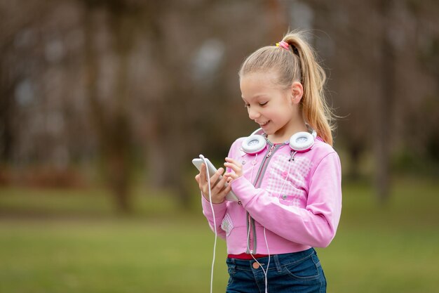 Gelukkig mooi meisje luisteren muziek van slimme telefoon in het park.