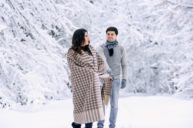 Gelukkig mooi paar bedekt met een warme deken met plezier in een besneeuwd park