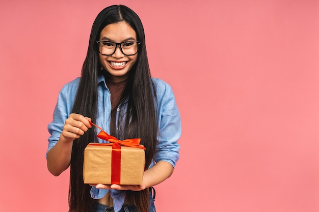 Gelukkig mooie Aziatische vrouw met geschenkdoos geïsoleerd op roze achtergrond tienermeisjes verliefd Ontvangen van geschenken van geliefden Nieuwjaar Kerstmis en Valentijnsdag concept