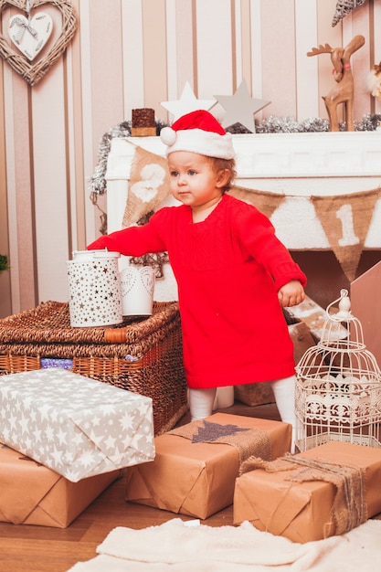 Gelukkig mooie baby gekleed in kostuum Kerstman met kerstcadeaus