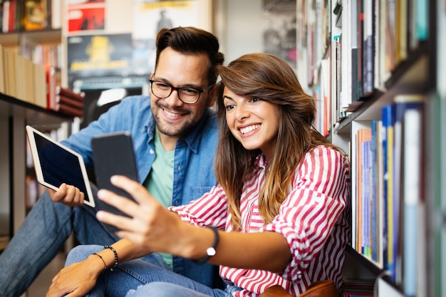 Gelukkig mooie hipster liefde student paar nemen van een selfie in schoolbibliotheek.