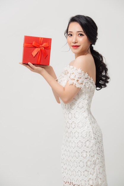 Gelukkig mooie jonge Aziatische vrouw met geschenkdoos geïsoleerd op witte achtergrond