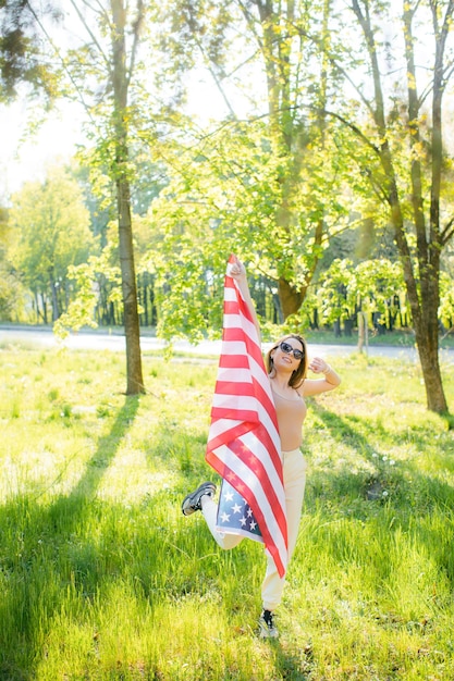 Gelukkig mooie jonge vrouw houdt een vlag patriottische vakantie en viering onafhankelijkheidsdag van de VS 4e