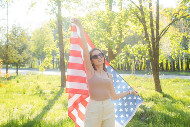 Gelukkig mooie jonge vrouw houdt een vlag patriottische vakantie en viering onafhankelijkheidsdag van de VS 4e