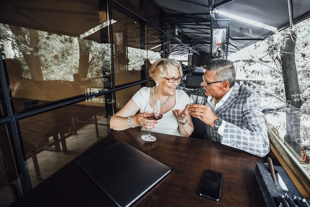 Gelukkig mooie ouderen drinken wijn op het zomerterras van de tablein in het moderne café