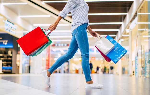 Gelukkig mooie stijlvolle jongedame met boodschappentassen wandelen in het winkelcentrum