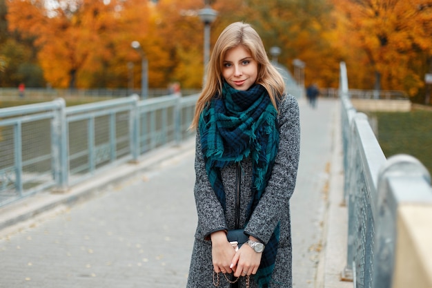 Gelukkig mooie vrouw in modieuze herfstkleren op brug in herfstdag