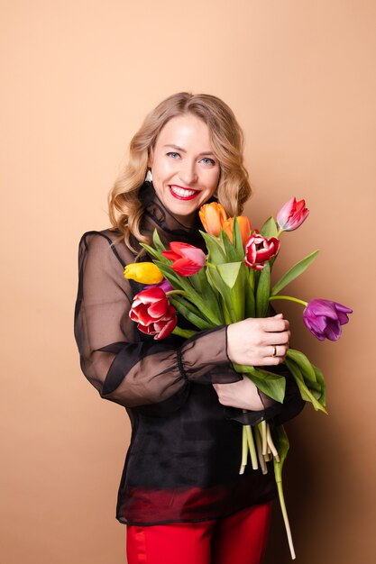 Gelukkig mooie vrouw poseren met bloemen en lachen