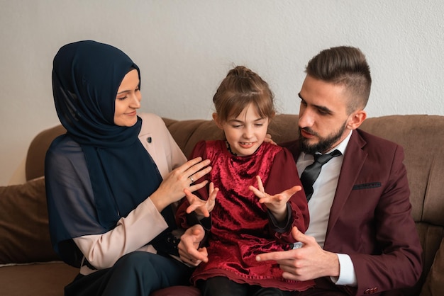 Gelukkig moslim familieportret Lachende ouders en hun schattige dochtertje poseren samen