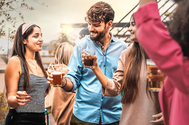 Gelukkig multi-etnische groep vrienden op universiteitsklasgenoten feest met plezier op het terras bier drinken en drank dansen en levendige filter hechten