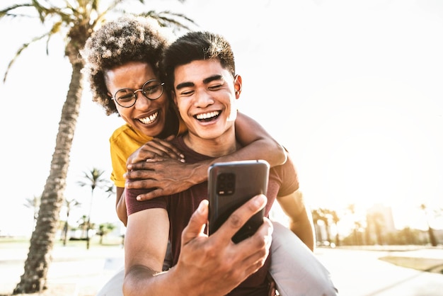 Gelukkig multiraciaal paar dat slim mobiel telefoonapparaat buiten gebruikt