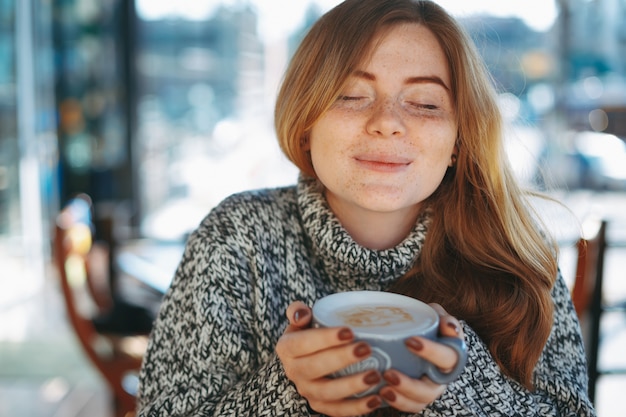 Gelukkig natuurlijk roodachtig meisje dat een grote kop van koffie drinkt