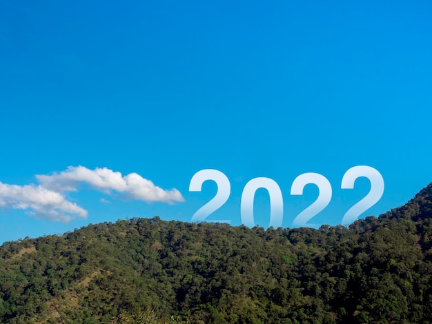 Gelukkig nieuwjaar 2022 met grote letters op de weelderige groene vruchtbare bergen en blauwe lucht, prachtig uitzicht met kopieerruimte, een succesvol concept. Welkom, prettige kerstdagen en een gelukkig nieuwjaar in 2022.