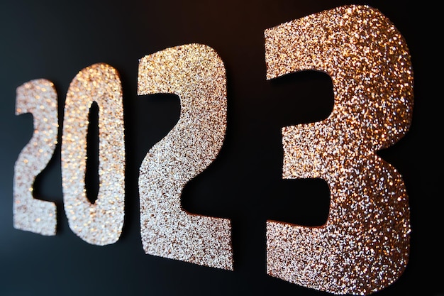 Foto gelukkig nieuwjaar 2023 gouden cijfers op een zwarte achtergrond met glitters