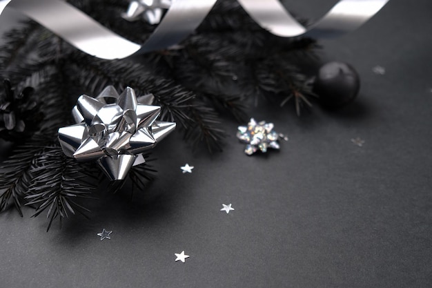 Gelukkig Nieuwjaar en Merry Christmas zwart concept. Achtergrond van zwarte takken van een kerstboom met zilveren decor op een zwarte achtergrond.