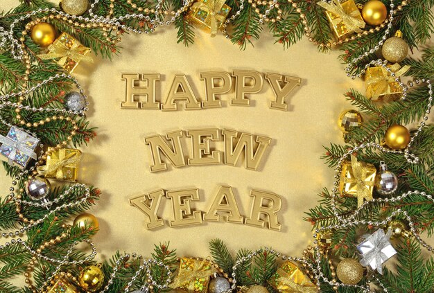 Gelukkig Nieuwjaar gouden tekst en vuren tak en kerstversiering op een gouden achtergrond