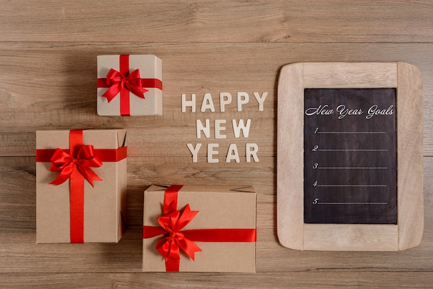 Gelukkig Nieuwjaar hout en Nieuwjaarsdoelen lijst geschreven op schoolbord met geschenkdoos