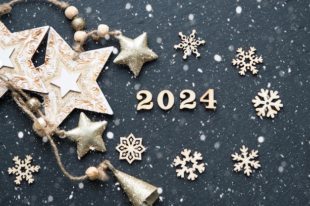 Foto gelukkig nieuwjaar houten letters en de cijfers 2024 op feestelijke zwarte achtergrond met pailletten sterren sneeuw begroetingen postkaart kalender omslag