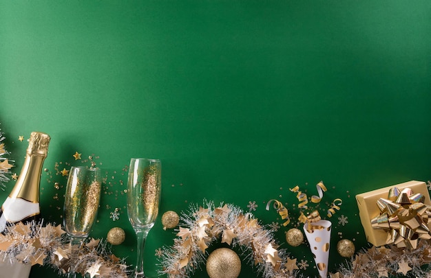 Gelukkig Nieuwjaar viering achtergrond concept. Champagne met glas, gouden lint, sterren en kerstbal op groene achtergrond.