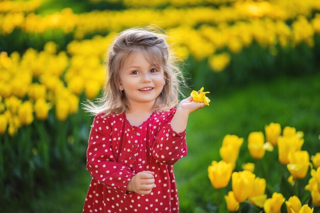 Gelukkig Oekraïens babymeisje op een bloeiend gazon van gele tulpen