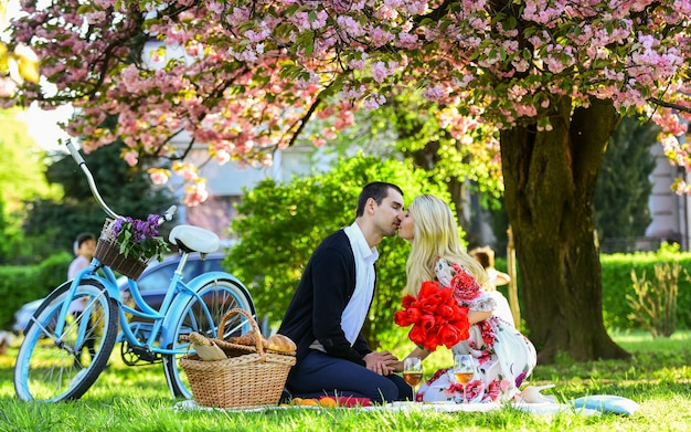 Gelukkig om verliefd te zijn romantisch paar op picknick liefde datum in het voorjaar ontspannen onder bloeiende sakura paar verliefd vieren verjaardag gelukkige familie in zomer park eten en drinken man en vrouw