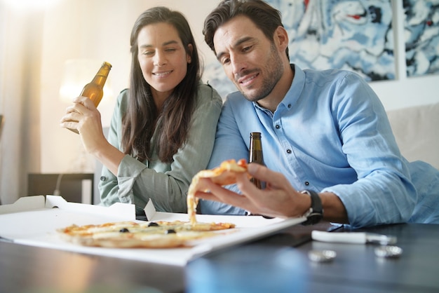 Gelukkig ontspannen paar dat een pizza thuis deelt