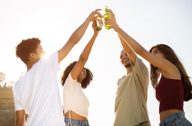 Gelukkig opgewonden jonge diverse mensen spelen cheers flessen drinken op picknick veel plezier op het strand