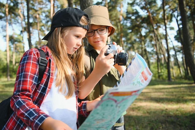 Gelukkig opgewonden schoolkinderen met rugzakken in casual kleding genieten van wandelen in het bos op zonnige herfstdag twee actieve kinderen jongen en meisje samen rennen en spelen tijdens kampeertrip in de natuur