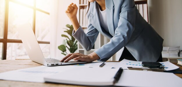 Gelukkig opgewonden succesvolle zakelijke Aziatische vrouw zegevieren in kantoor Portret van een vrolijke Aziatische zakenvrouw zitten aan de tafel in kantoor