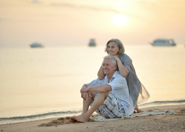 Gelukkig ouder paar ontspannen op het strand bij zonsondergang