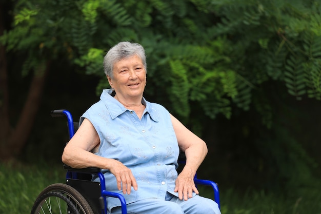 Gelukkig oudere gehandicapte vrouw zittend in een rolstoel buitenshuis