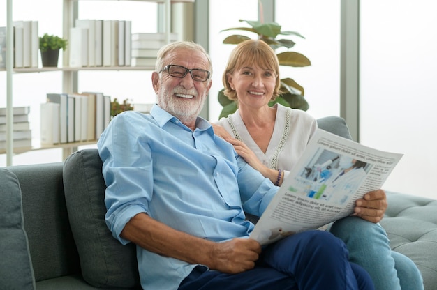 Gelukkig paar blanke senioren ontspannen, lezen de krant in de woonkamer