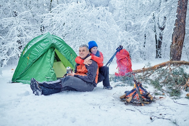 Gelukkig paar boven een kampvuur in besneeuwd winterbos