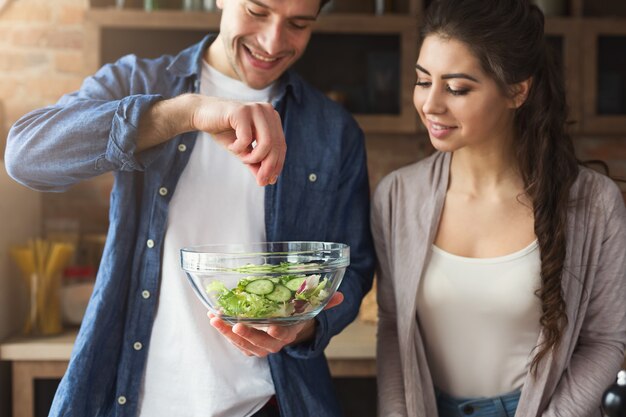 Gelukkig paar dat het diner samen voorbereidt in hun loftkeuken thuis. Groentesalade maken.