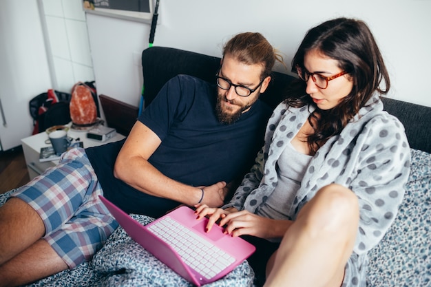 Gelukkig paar dat in bed ligt dat binnen computer bekijkt