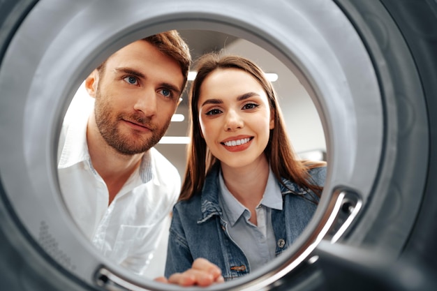 Gelukkig paar dat nieuwe wasmachine kiest in een winkel vanuit de binnenkant van de wasmachine