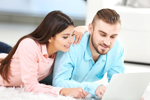 Gelukkig paar dat op de vloer ligt en aan laptop werkt