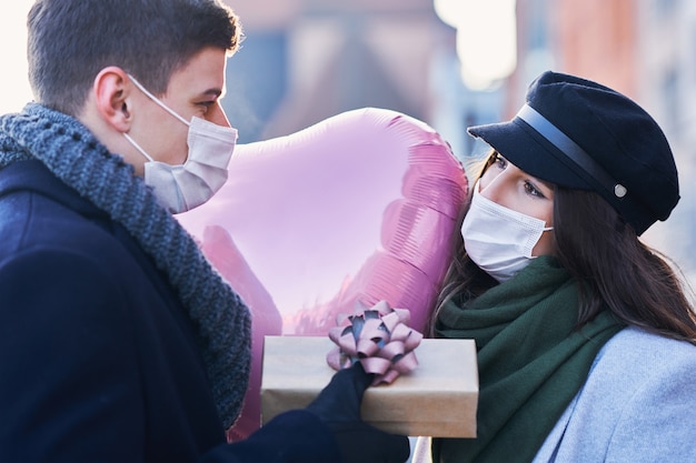 Gelukkig paar dat Valentijnsdag in maskers viert tijdens de covid-19-pandemie in de stad