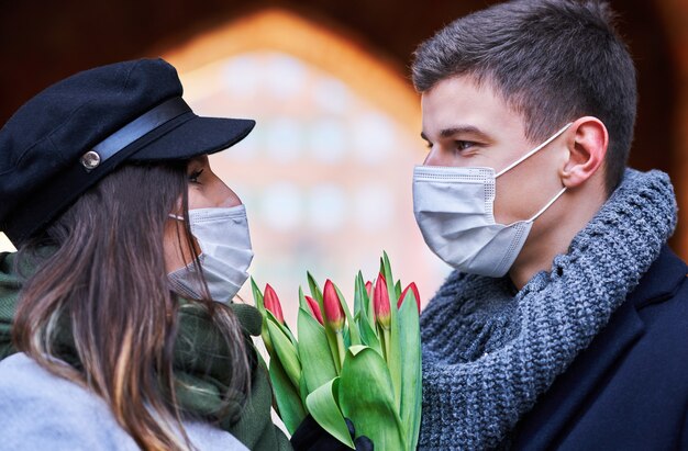 Gelukkig paar dat Valentijnsdag in maskers viert tijdens de covid-19-pandemie in de stad