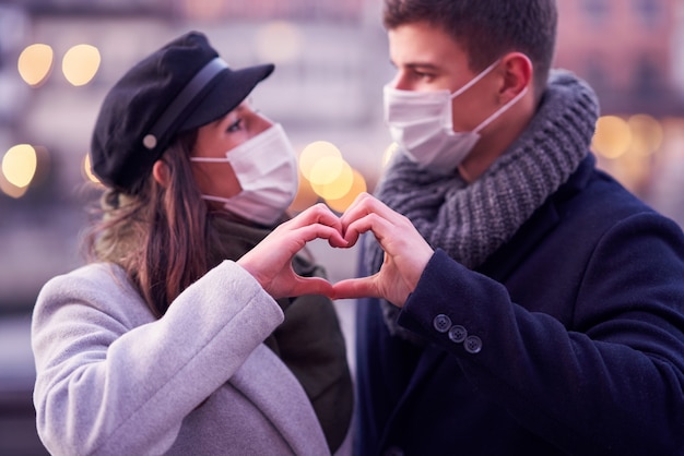 Gelukkig paar dat valentijnsdag in maskers viert tijdens de covid-19-pandemie in de stad