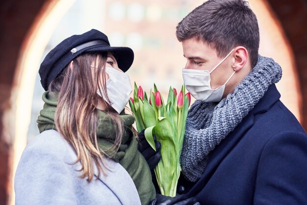 Gelukkig paar dat valentijnsdag in maskers viert tijdens de covid-19-pandemie in de stad