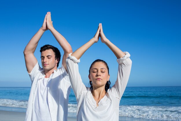 Gelukkig paar dat yoga naast het water doet