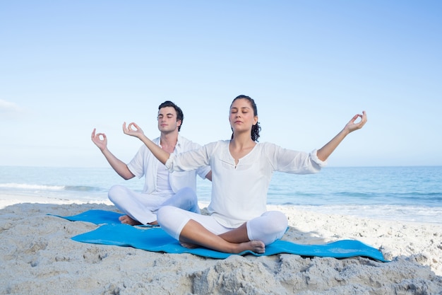 Gelukkig paar dat yoga naast het water doet