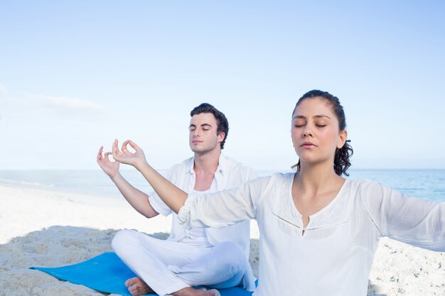 Gelukkig paar dat yoga naast het water doet