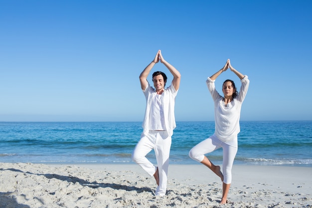 Gelukkig paar dat yoga naast het water doet